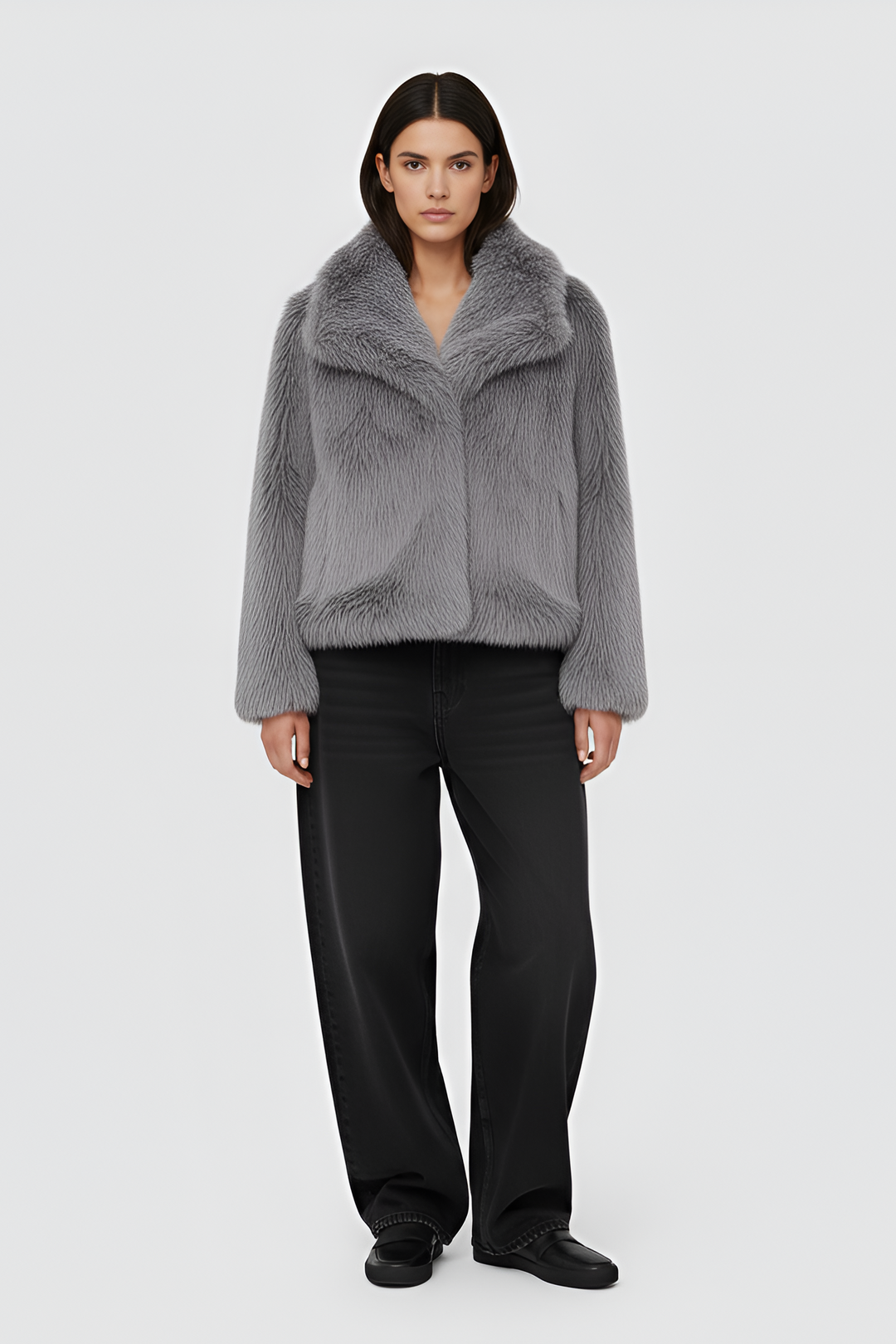 Woman wearing a gray fur coat over a white outfit on a plain background