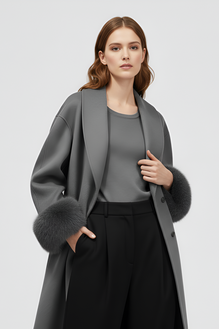 Woman wearing a gray coat with fur trim on a light gray background