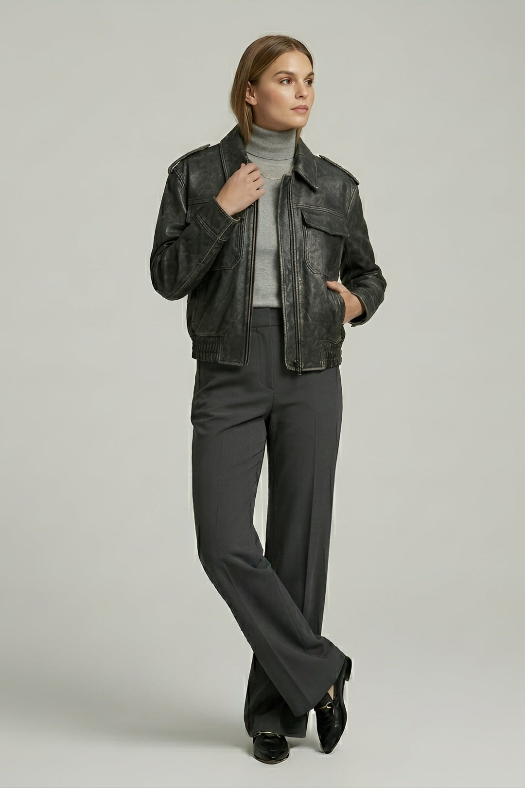 Woman wearing a gray jacket and pants on a plain background