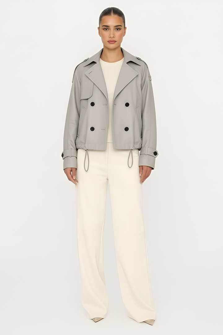 Woman wearing a gray jacket and white pants on a white background