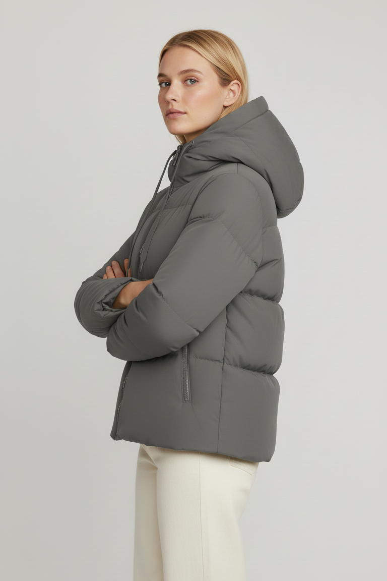 Woman wearing a gray puffer jacket on a plain background