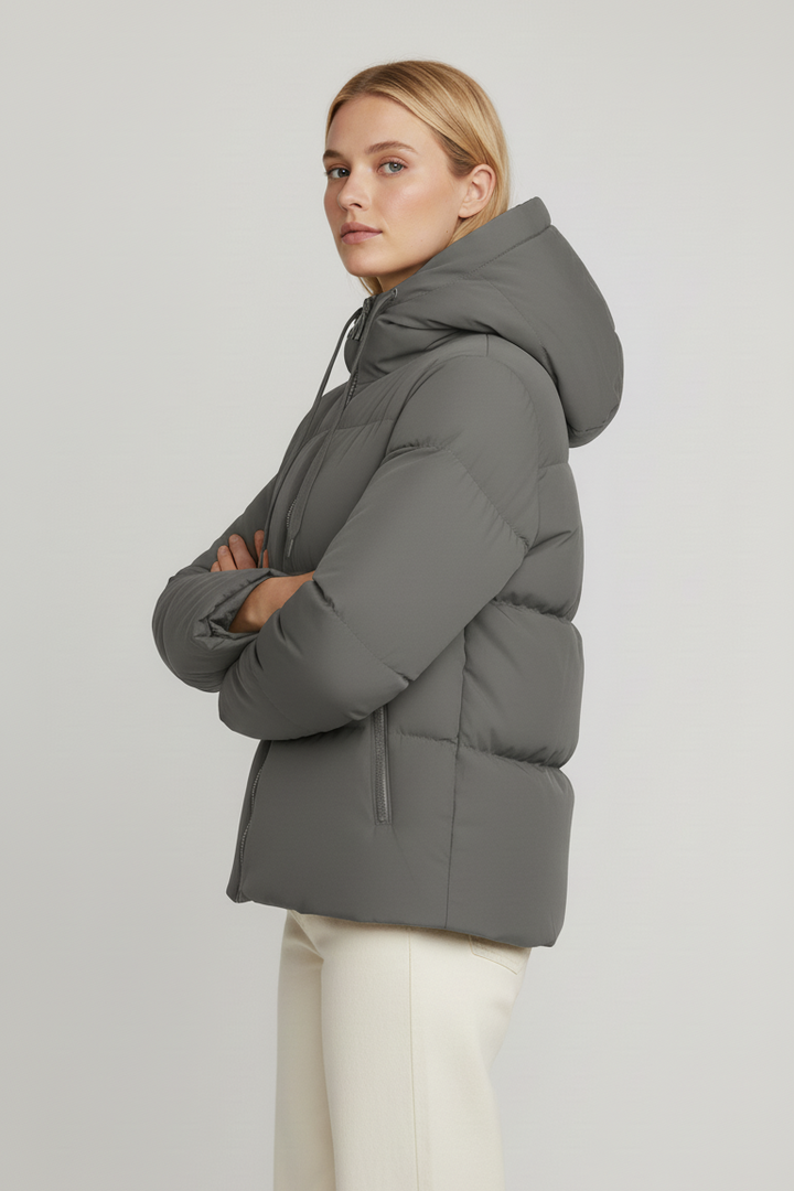 Woman wearing a gray puffer jacket on a plain background