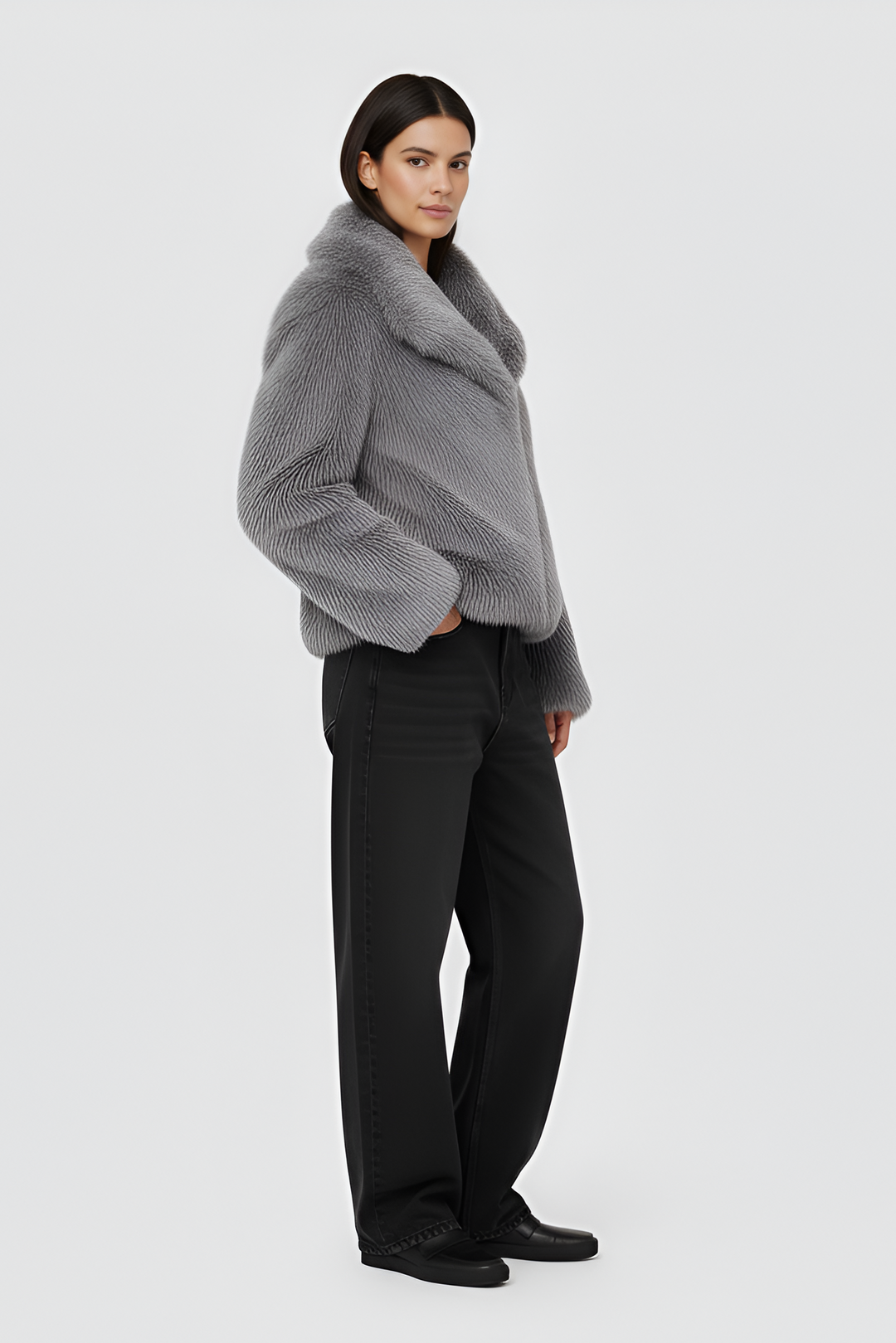 Woman wearing a gray fur coat over a white outfit on a plain background