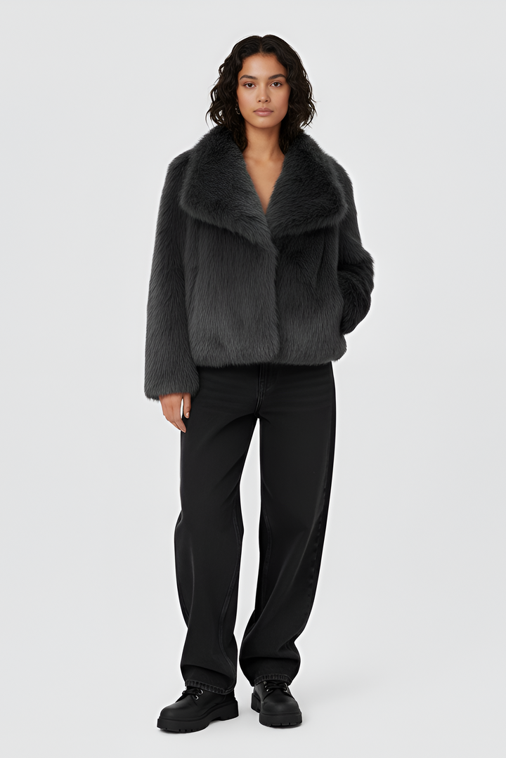 Woman wearing a gray sweater and white skirt on a plain background