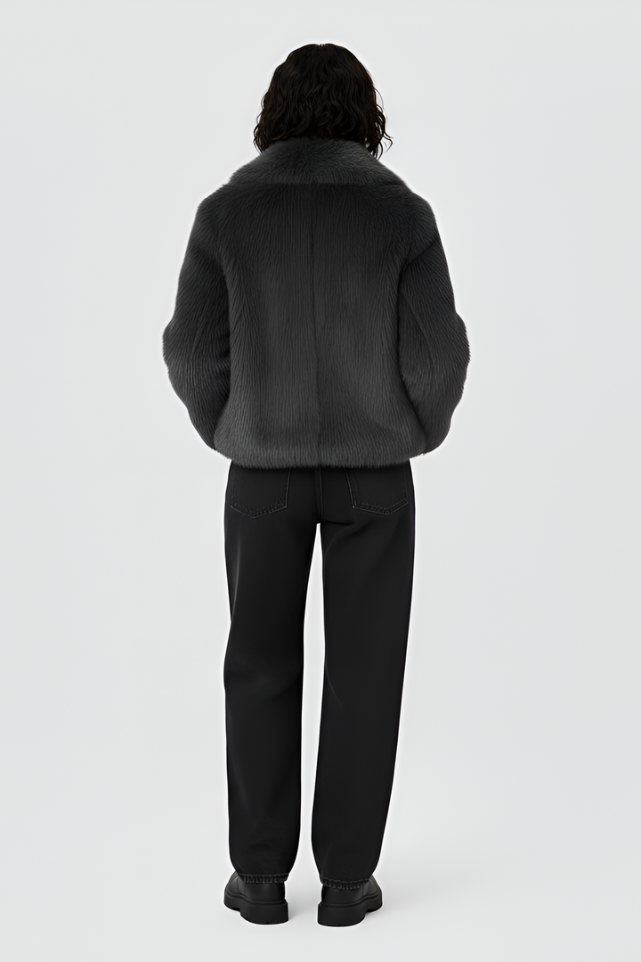 Woman wearing a gray sweater and white skirt on a plain background