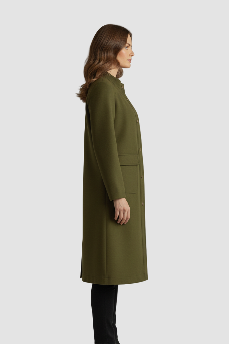 Woman wearing a green coat standing against a plain background