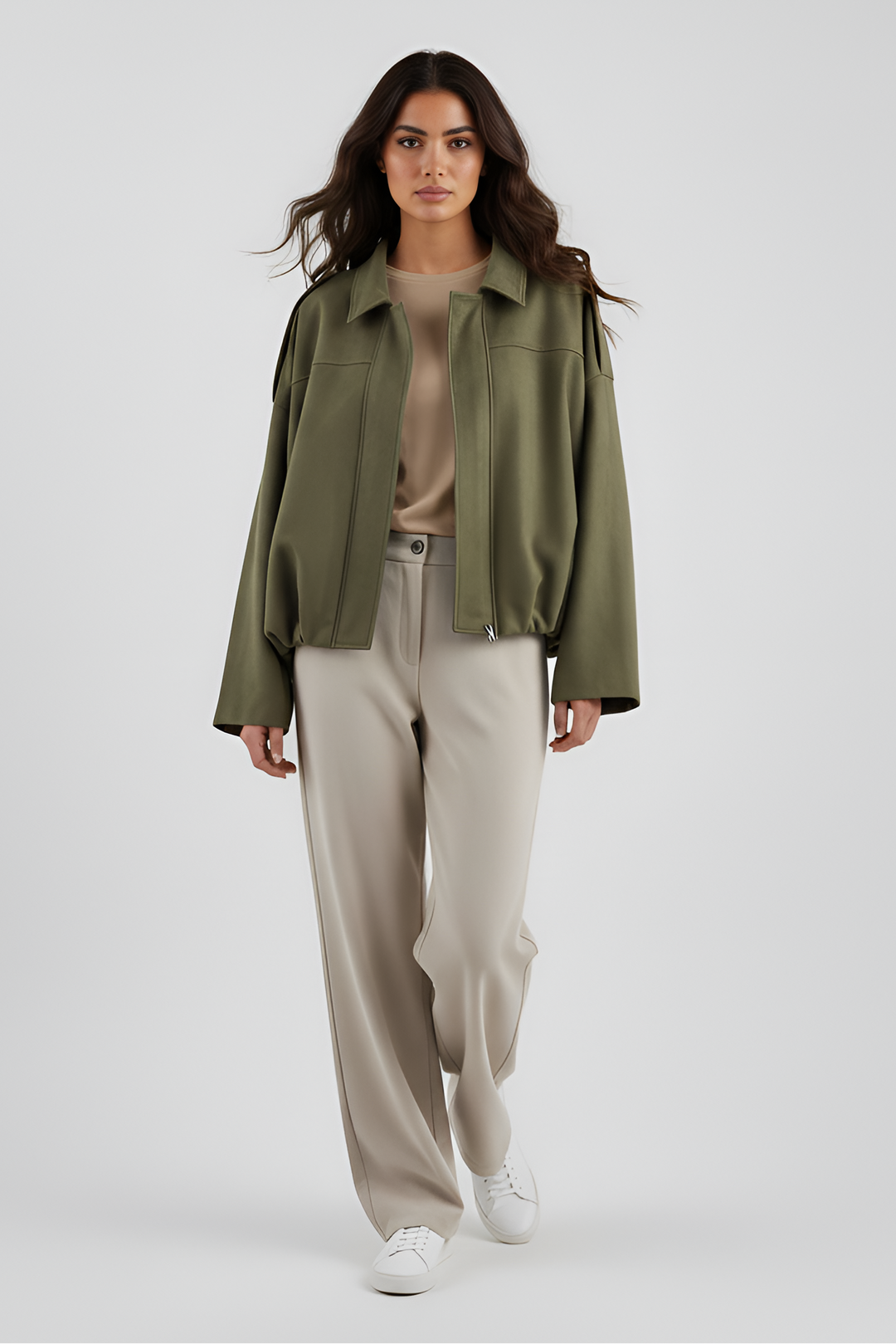 Woman wearing a green jacket and beige pants on a white background