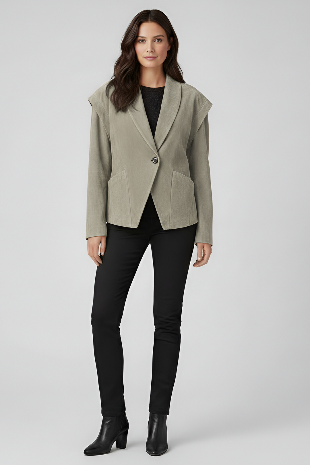Woman wearing a light gray blazer over a black top and pants on a white background