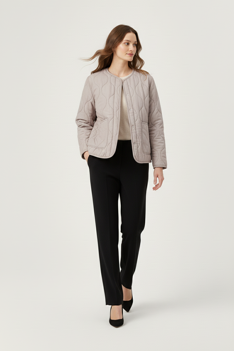 Woman wearing a light gray jacket and black pants on a white background