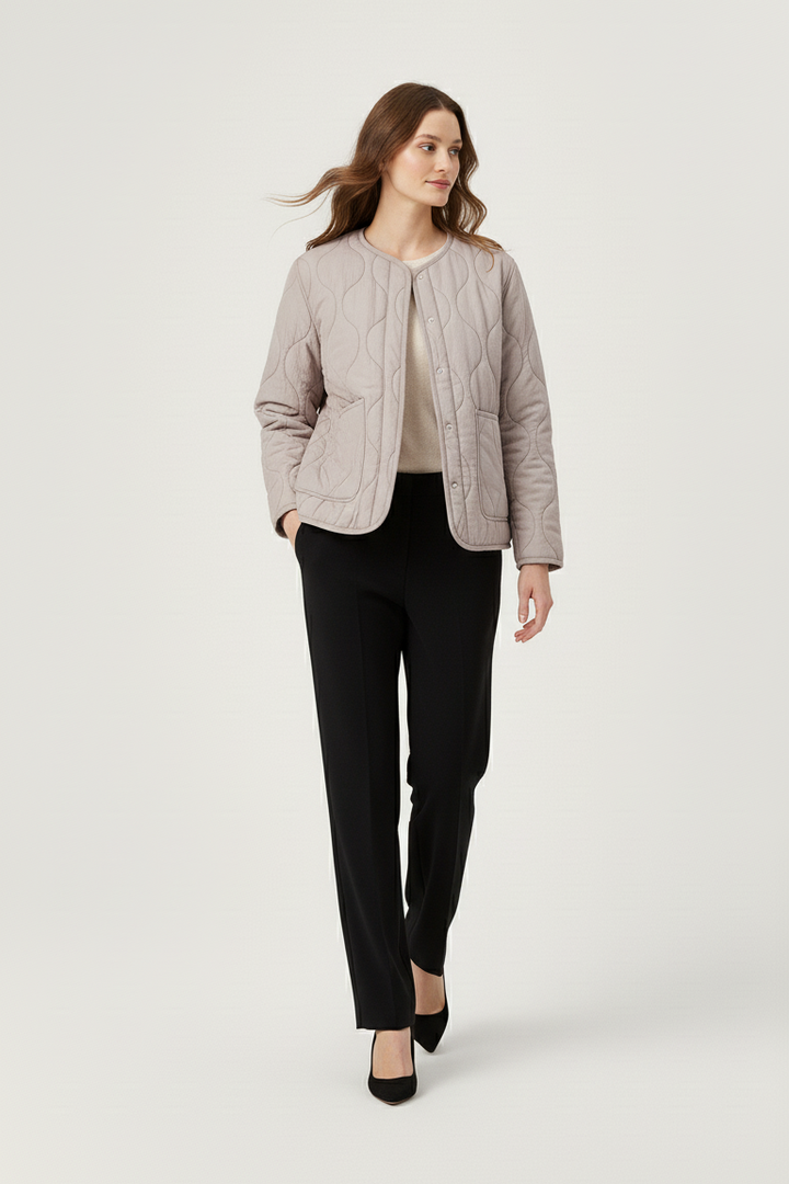 Woman wearing a light gray jacket and black pants on a white background