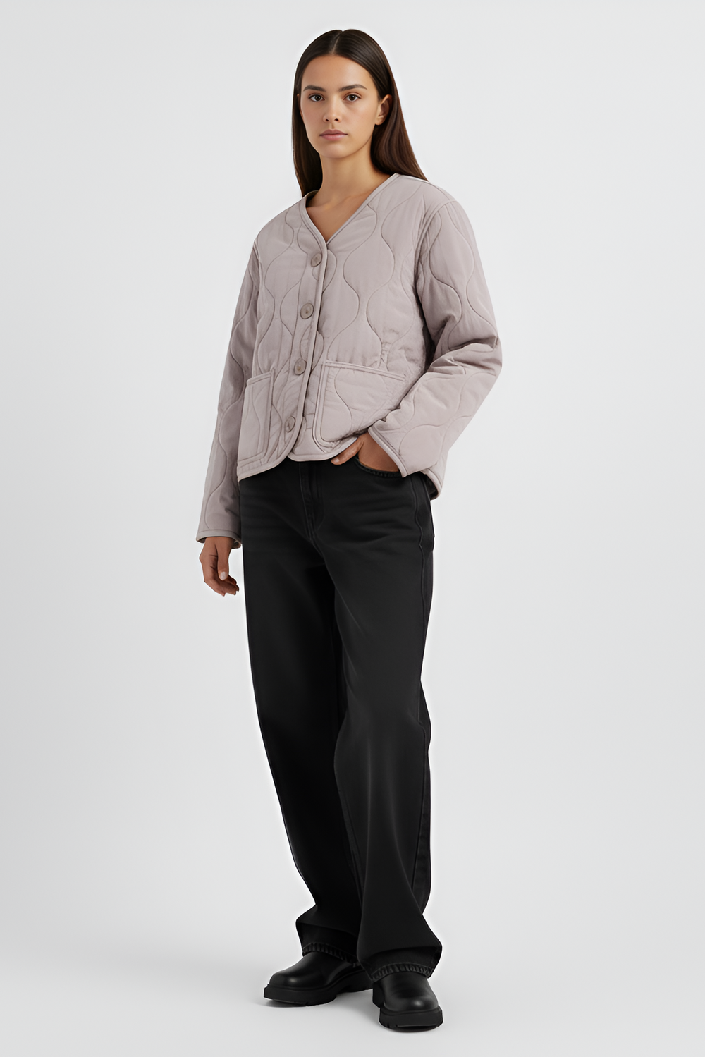 Woman wearing a light gray quilted jacket and black pants on a white background