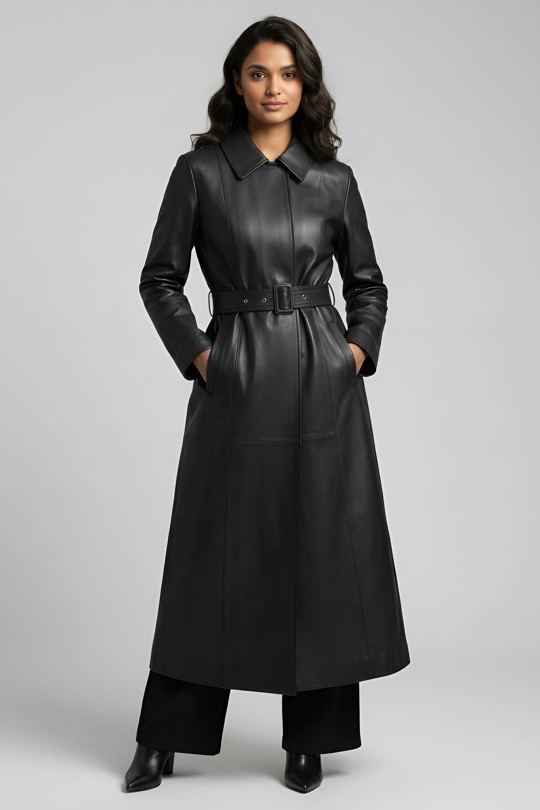 Woman wearing a long black leather coat on a gray background