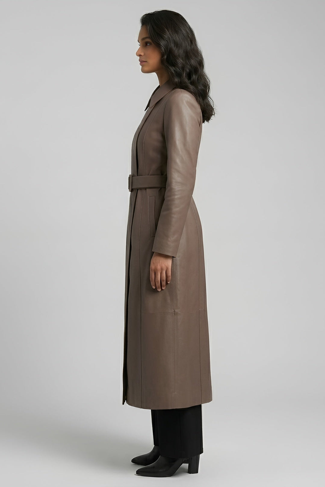 Woman wearing a long brown coat on a plain background