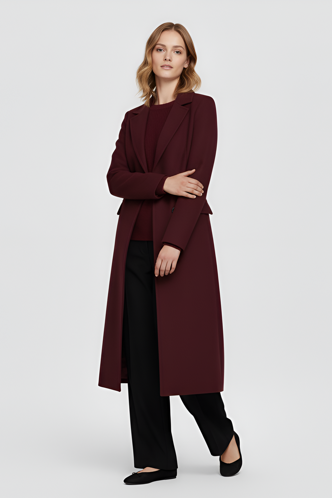 Woman wearing a long burgundy coat on a light gray background