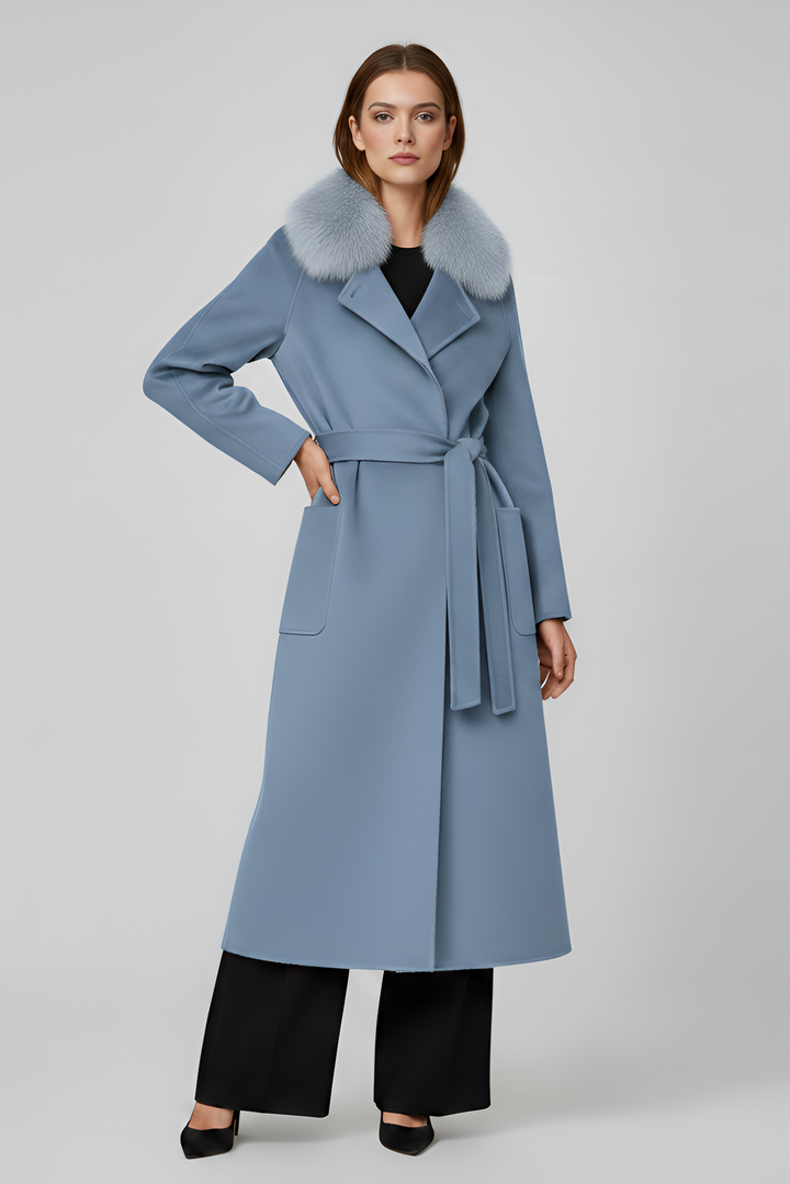 Woman wearing a long light blue coat with fur trim on a gray background