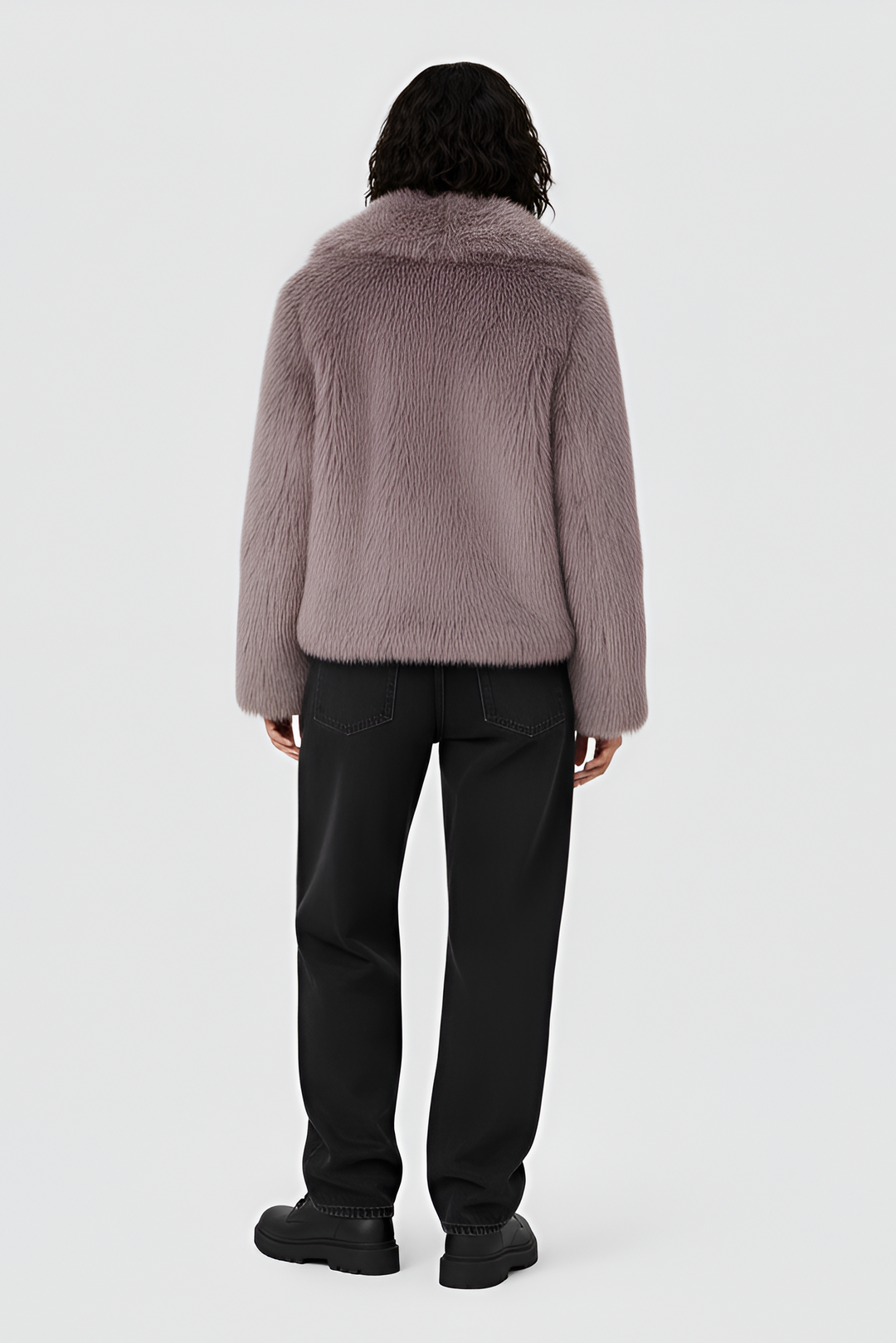 Woman wearing a pink fur coat, white top, and skirt on a plain background