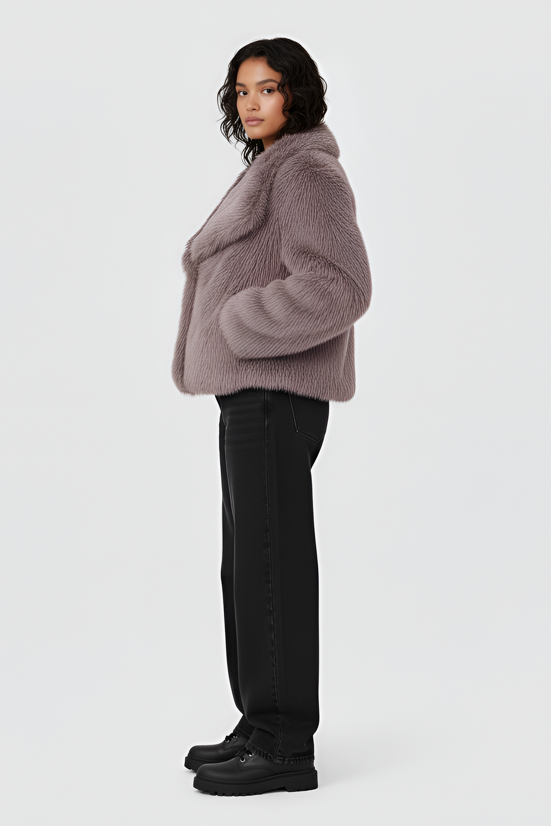 Woman wearing a pink fur coat, white top, and skirt on a plain background