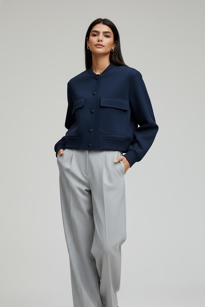 Woman wearing a navy jacket and light gray pants on a white background