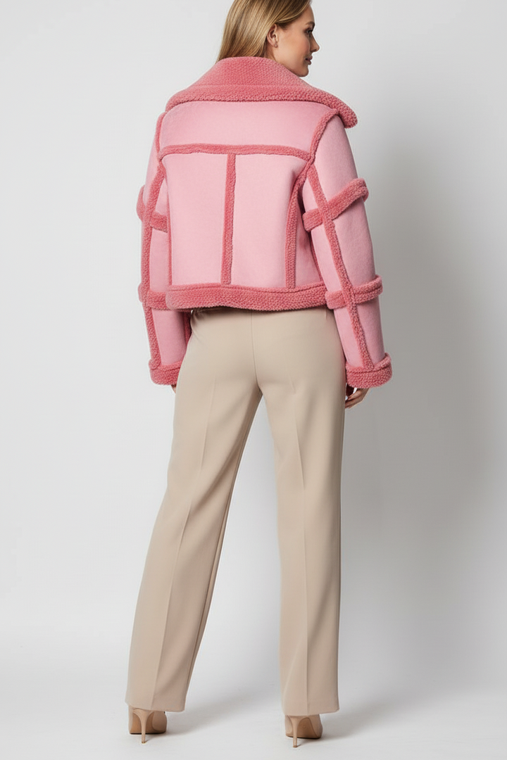 Woman wearing a pink jacket and beige pants on a white background