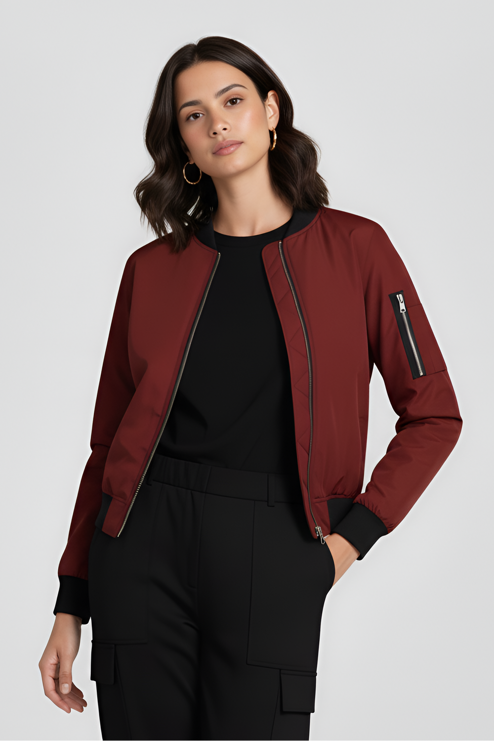 Woman wearing a red bomber jacket over a black top and pants on a white background