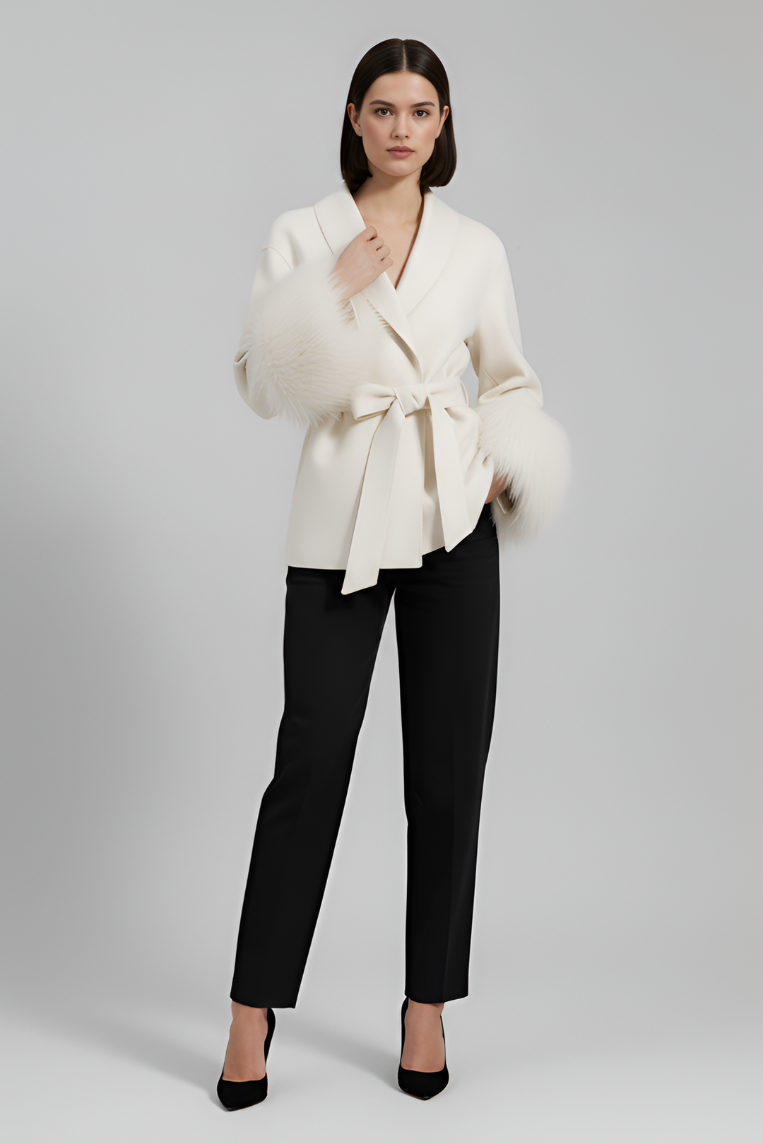 Woman wearing a white blazer and black pants on a gray background