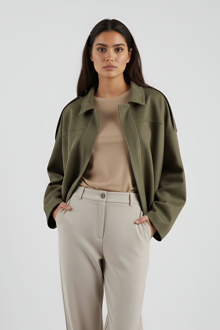 Woman wearing an olive green jacket and beige pants on a white background