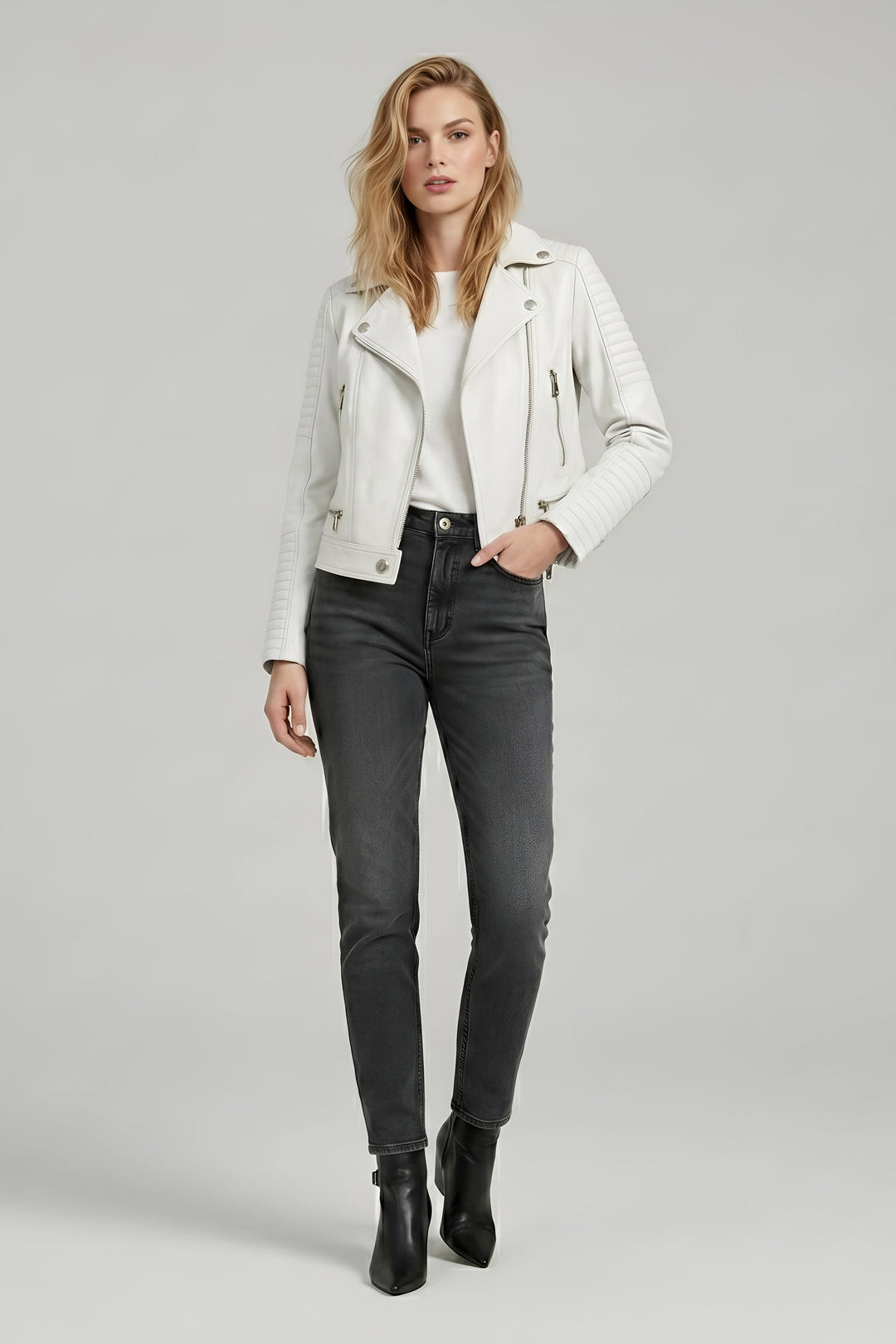 RYDER - Woman wearing a white leather biker jacket with a white top and grey jeans, front view, one hand in pocket
