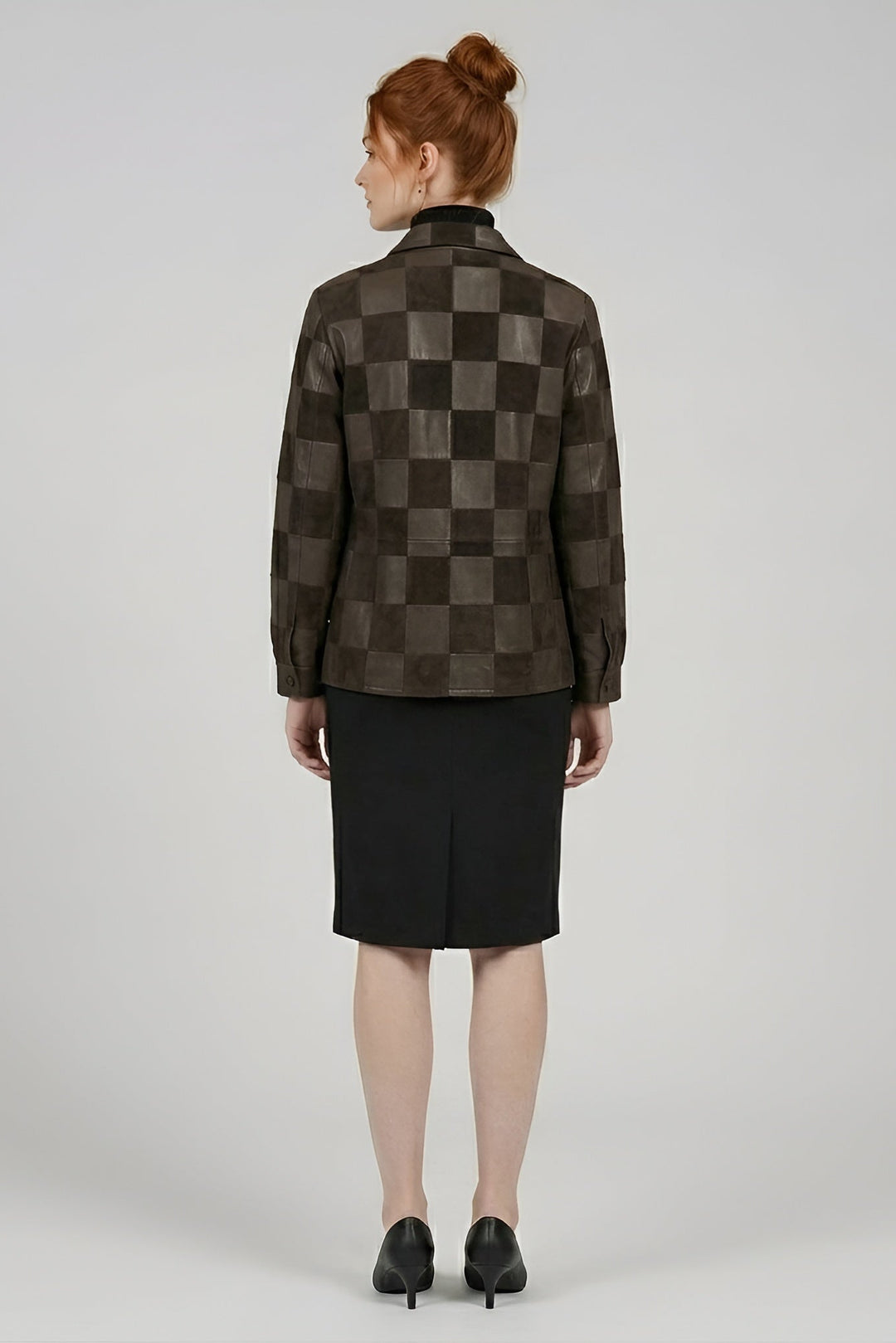 Person wearing a checkered jacket and black skirt on a plain background